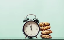 Pile de cookies à côté d'un réveil sur fond vert